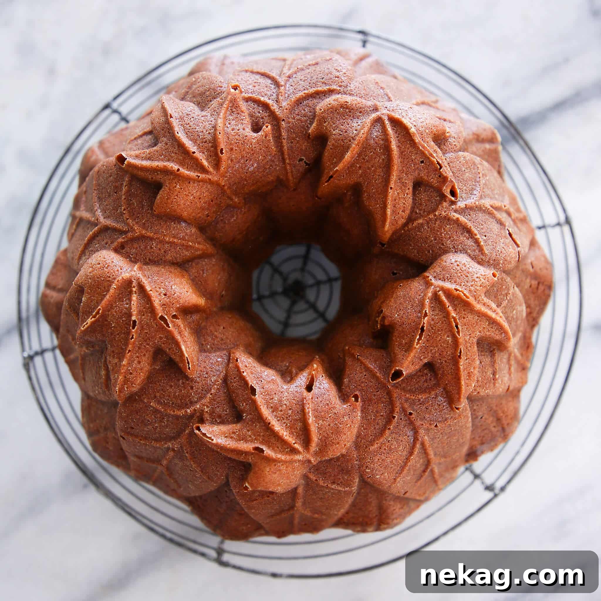 Pumpkin Harvest Bundt Bliss 4 A beautifully baked pumpkin spice bundt cake, still warm and unglazed, set against a backdrop of vibrant autumn leaves, highlighting its intricate design and readiness for a maple glaze.