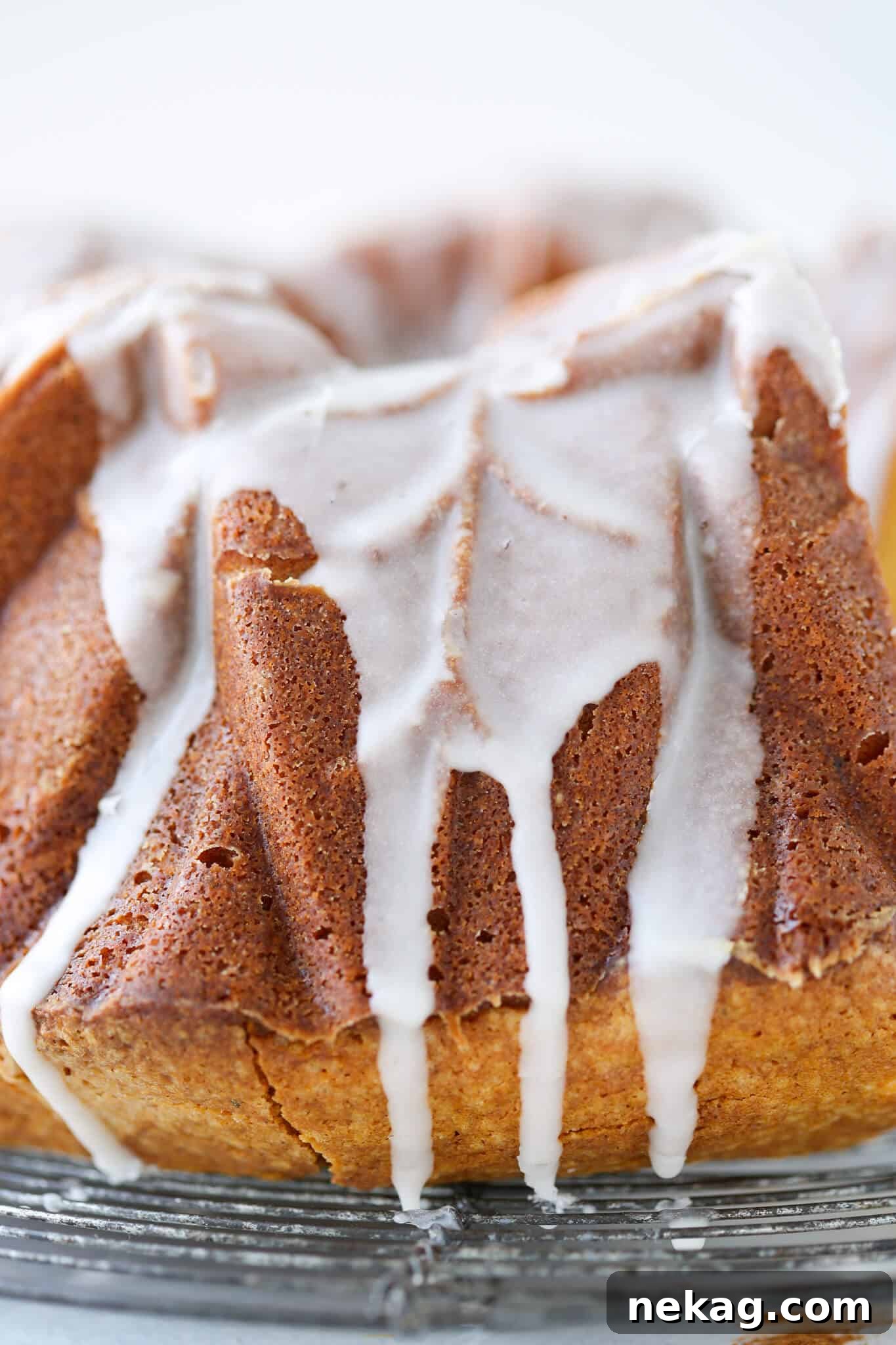 Pumpkin Harvest Bundt Bliss 7 A beautiful autumn bundt cake with maple glaze dripping down its sides, set on a rustic wooden board, emphasizing the rich fall colors and enticing texture.