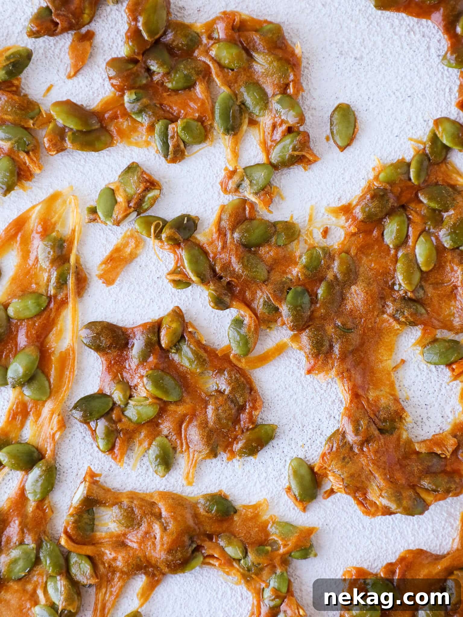 Caramelized pumpkin seed brittle scattered on a surface, highlighting its crunchy texture and golden hue.