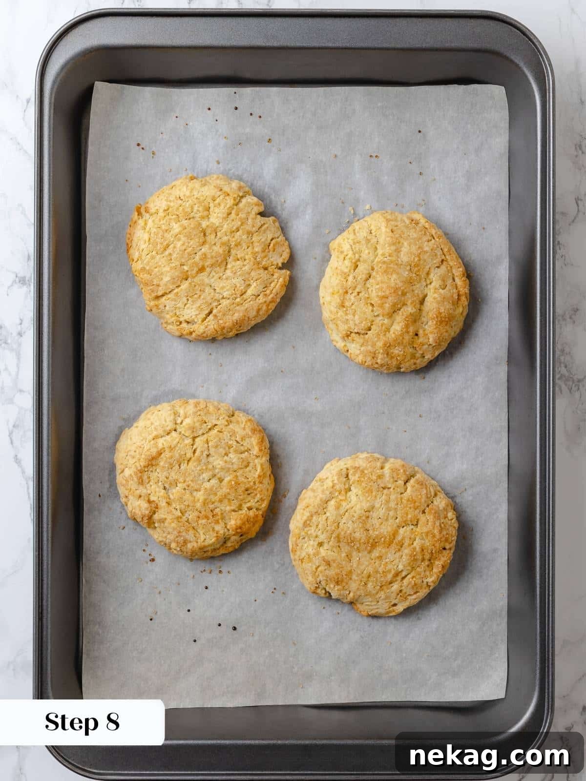 Baked shortcakes on a parchment-lined sheet, golden and crisp. Freshly baked shortcakes with golden-brown tops and crisp edges, cooling on a parchment-lined baking sheet.