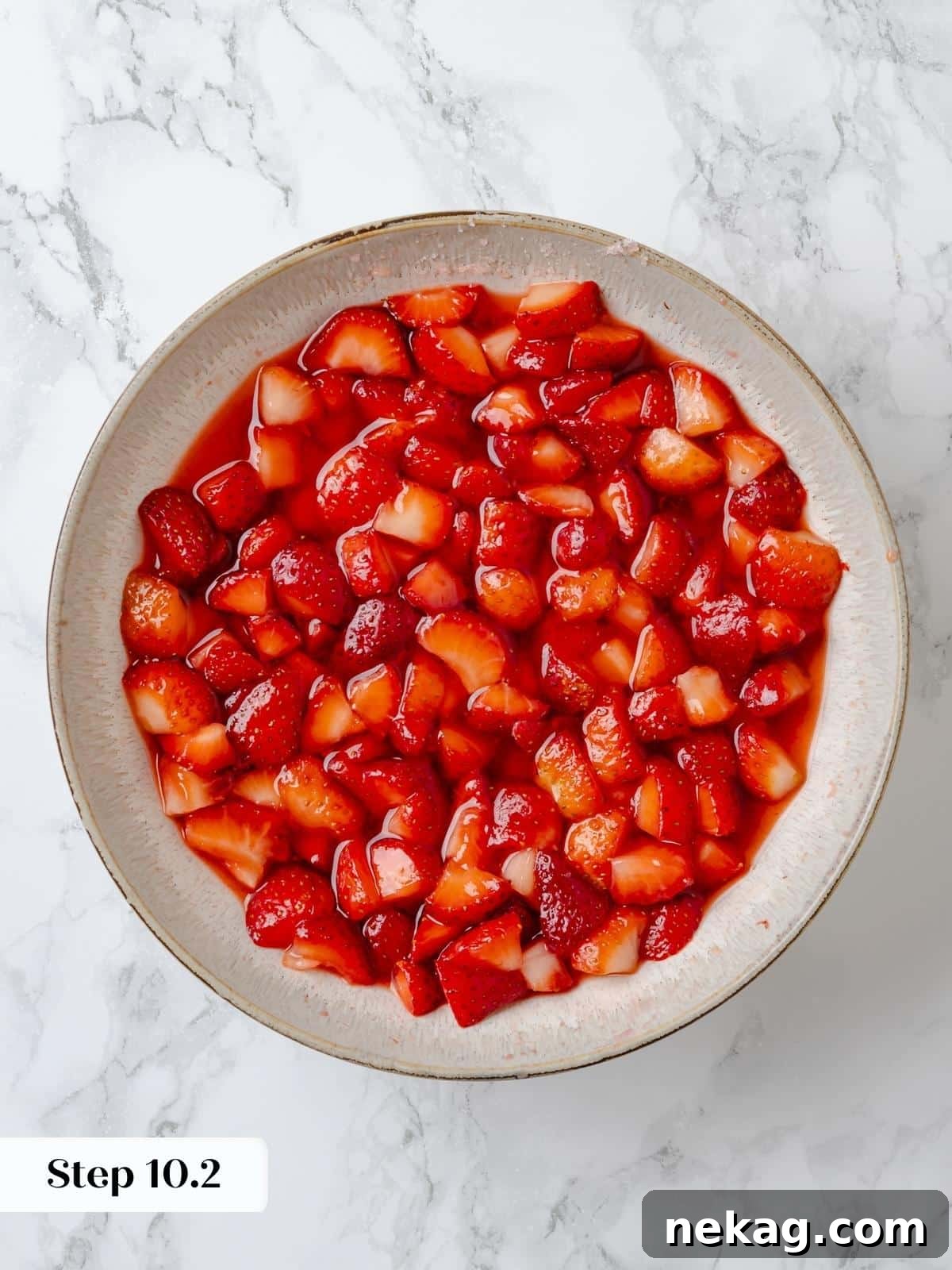 Macerated strawberries releasing juices in a glass bowl. A close-up of macerated strawberries in a glass bowl, showcasing the natural juices released from the berries, creating a rich syrup.