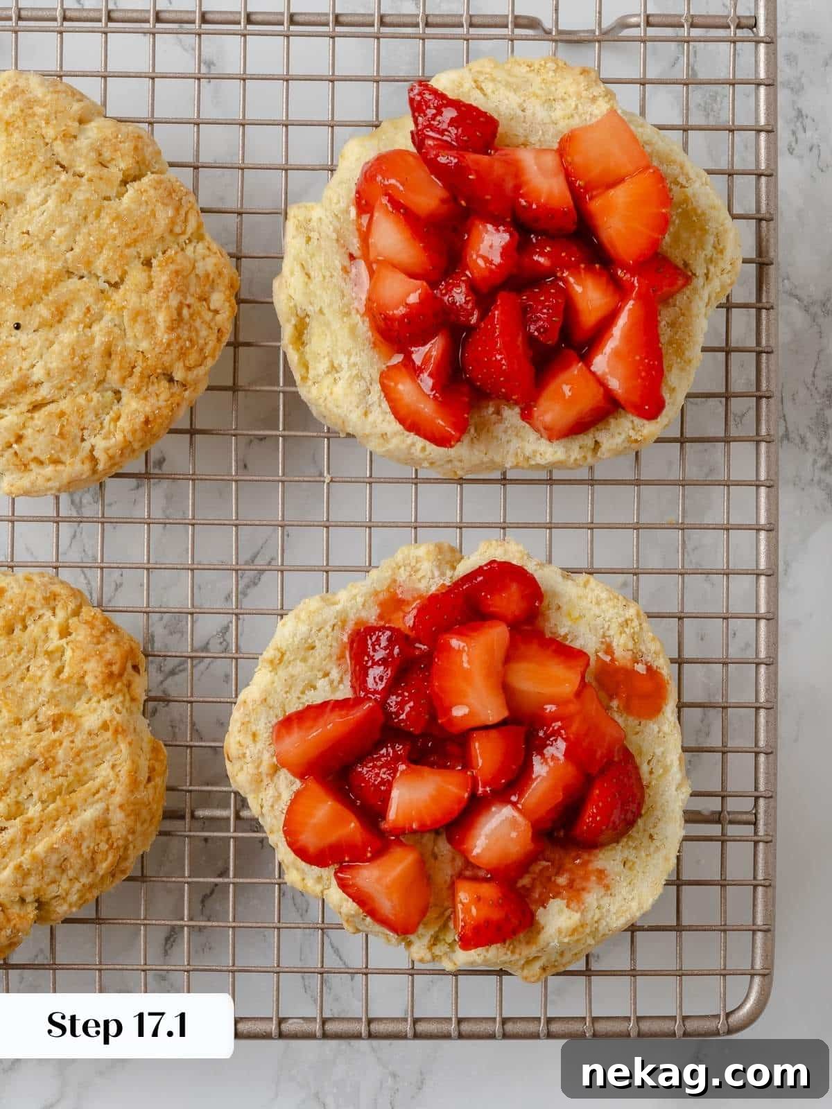 Fresh strawberries layered over shortcake biscuits in the assembly stage. Golden-brown shortcake biscuits topped with a generous layer of glistening fresh strawberries, ready for whipped cream.
