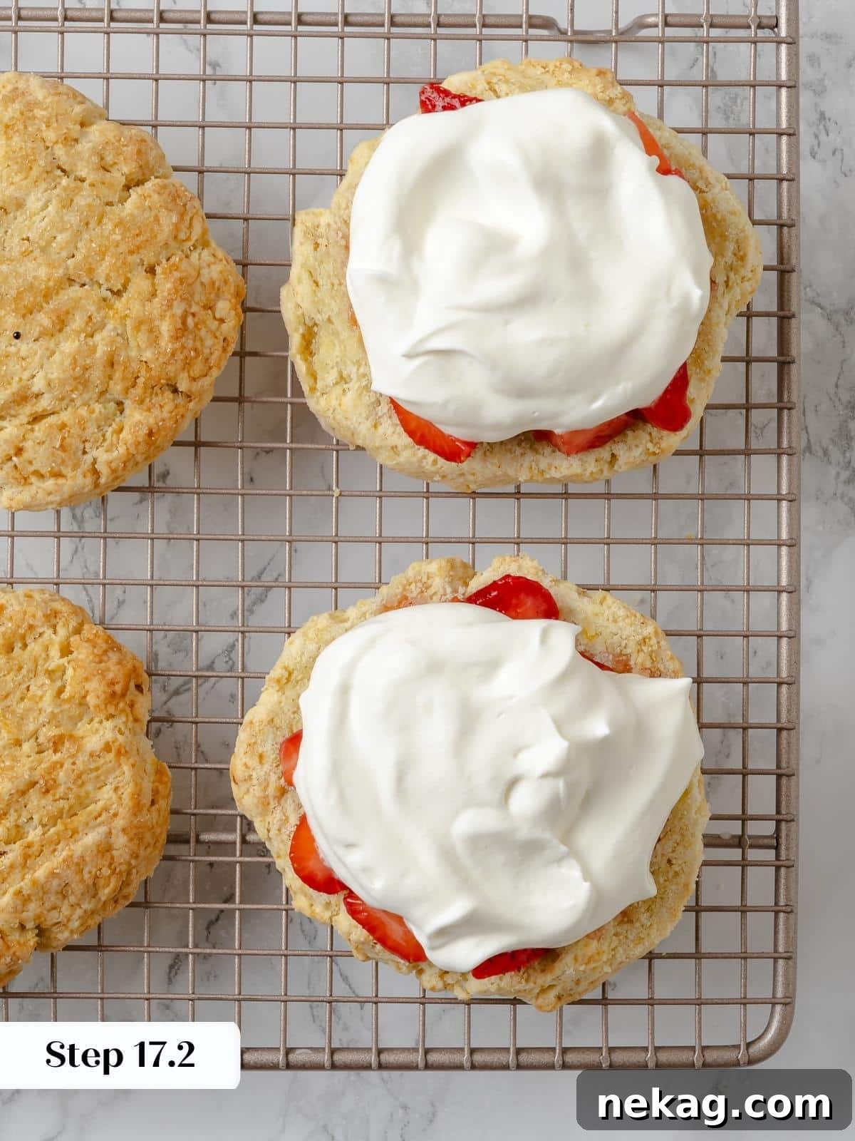 Shortcake halves filled with whipped cream and ready to be topped. Delicate shortcake halves generously filled with fluffy whipped cream, poised for the final layer of strawberries and the top biscuit.