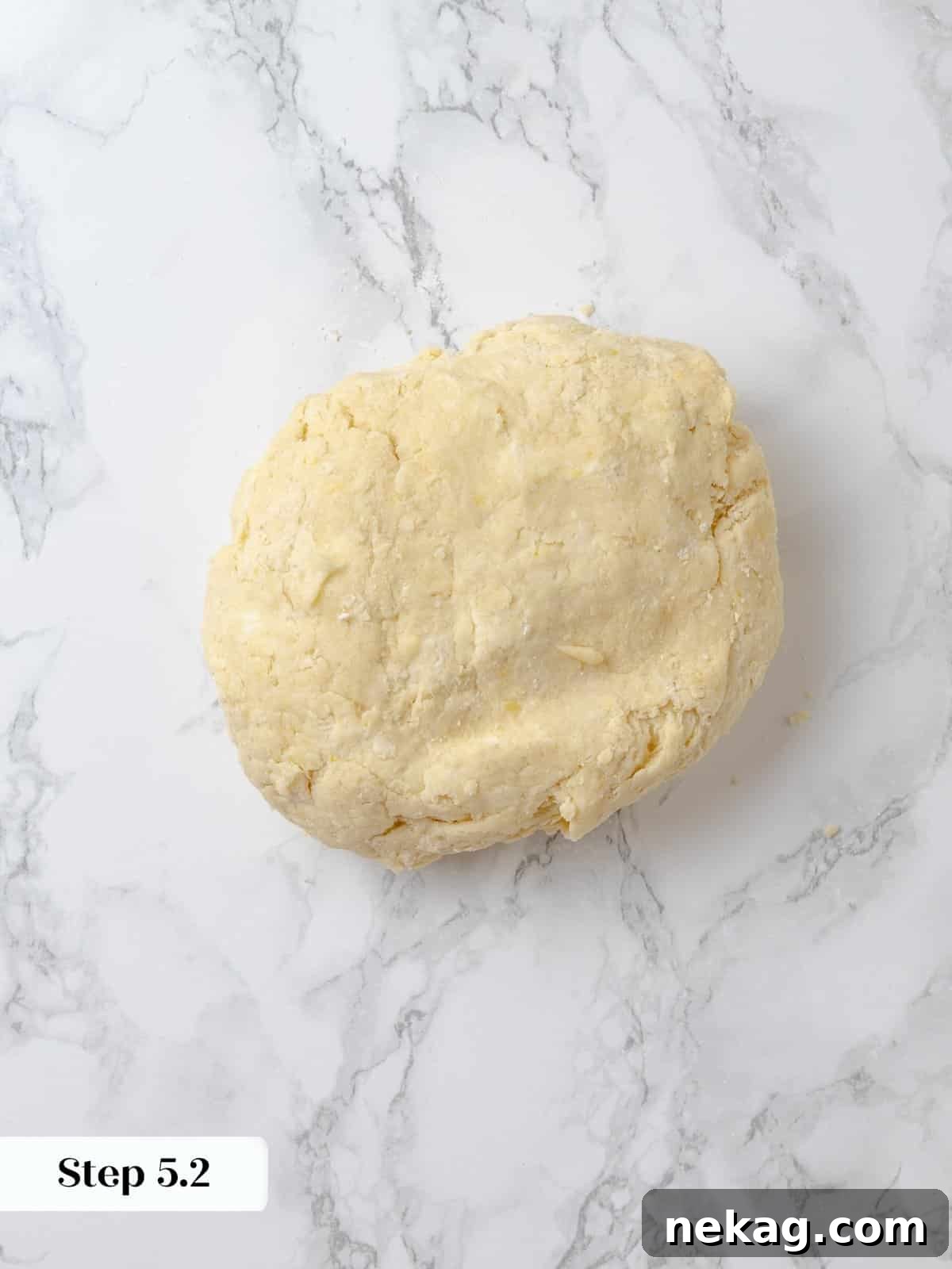 A soft, slightly sticky dough ball formed and ready to portion. A perfectly formed, soft dough ball sits in a mixing bowl, ready to be divided into individual shortcakes.