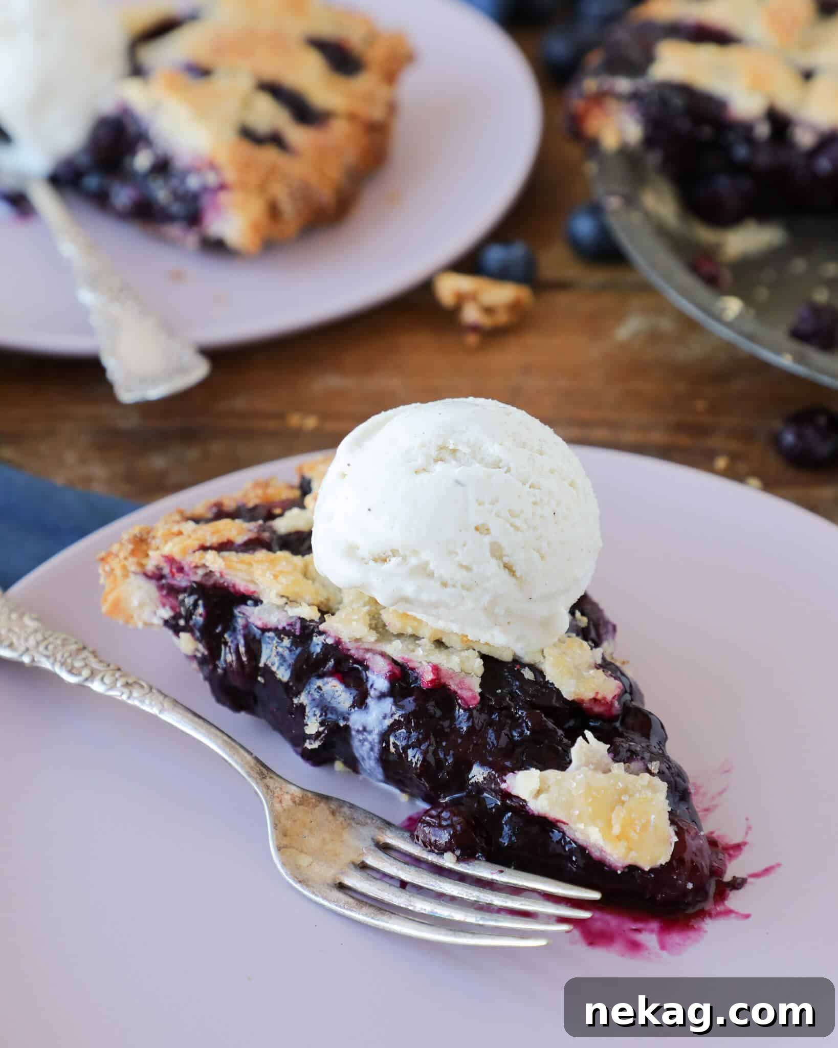 A perfectly sliced piece of blueberry pie on a light lavender plate, showcasing its thick, vibrant filling and golden crust.