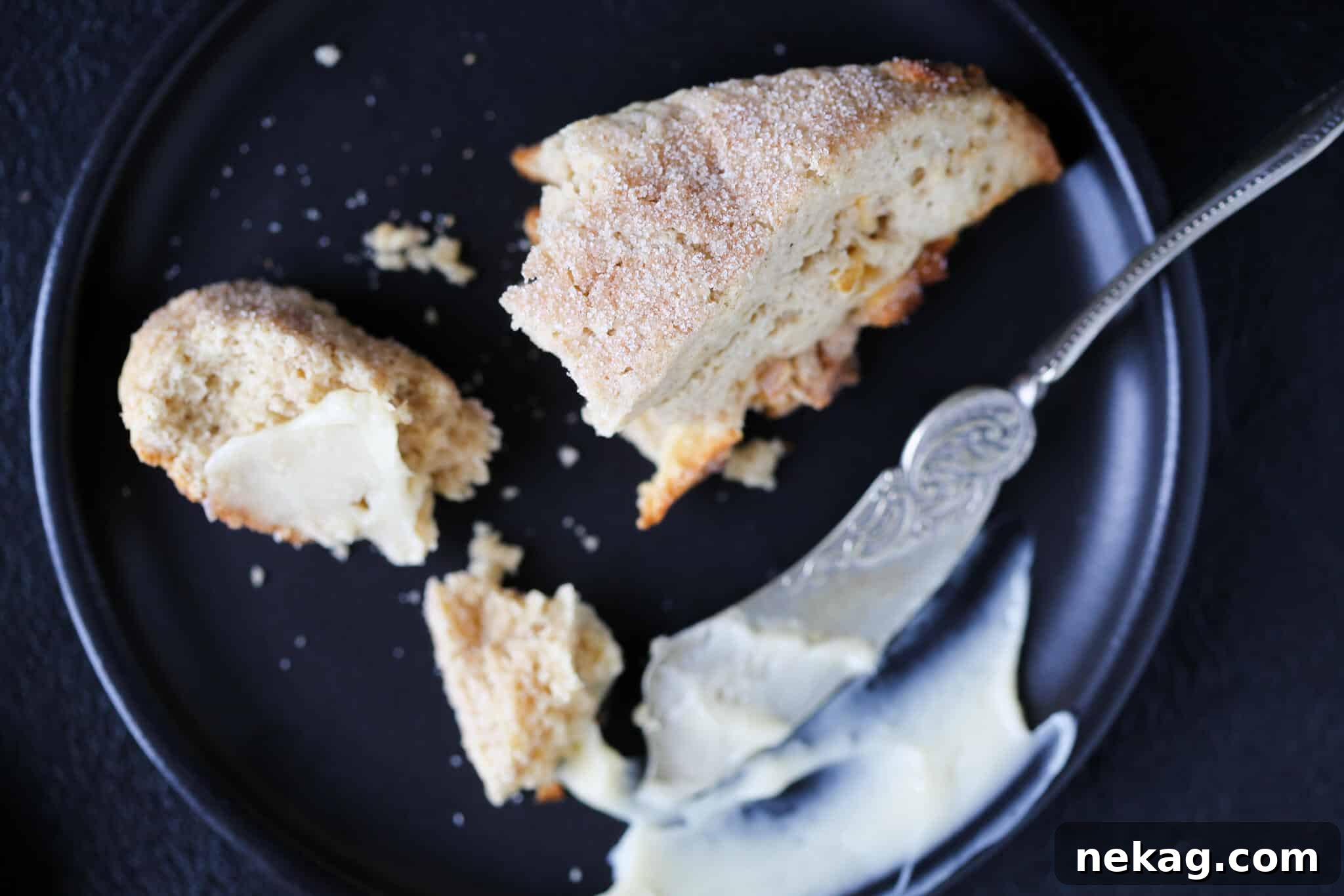 Close-up of a Spiced Apple Scone on a black plate, showcasing its tender texture.