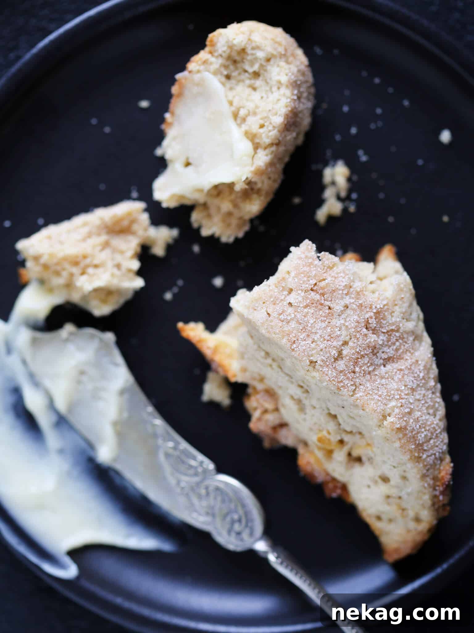 A silver knife resting on a perfectly baked spiced apple scone, ready to be sliced.