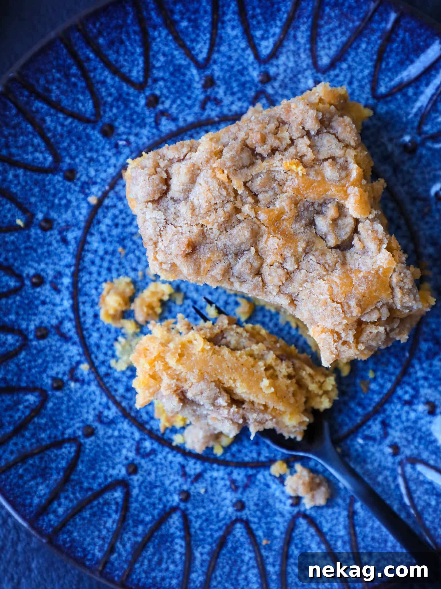 Spiced Pumpkin Crumble Cake 2 A delectable slice of pumpkin coffee cake displayed on a bright blue plate, highlighting its moist texture and crumb topping.