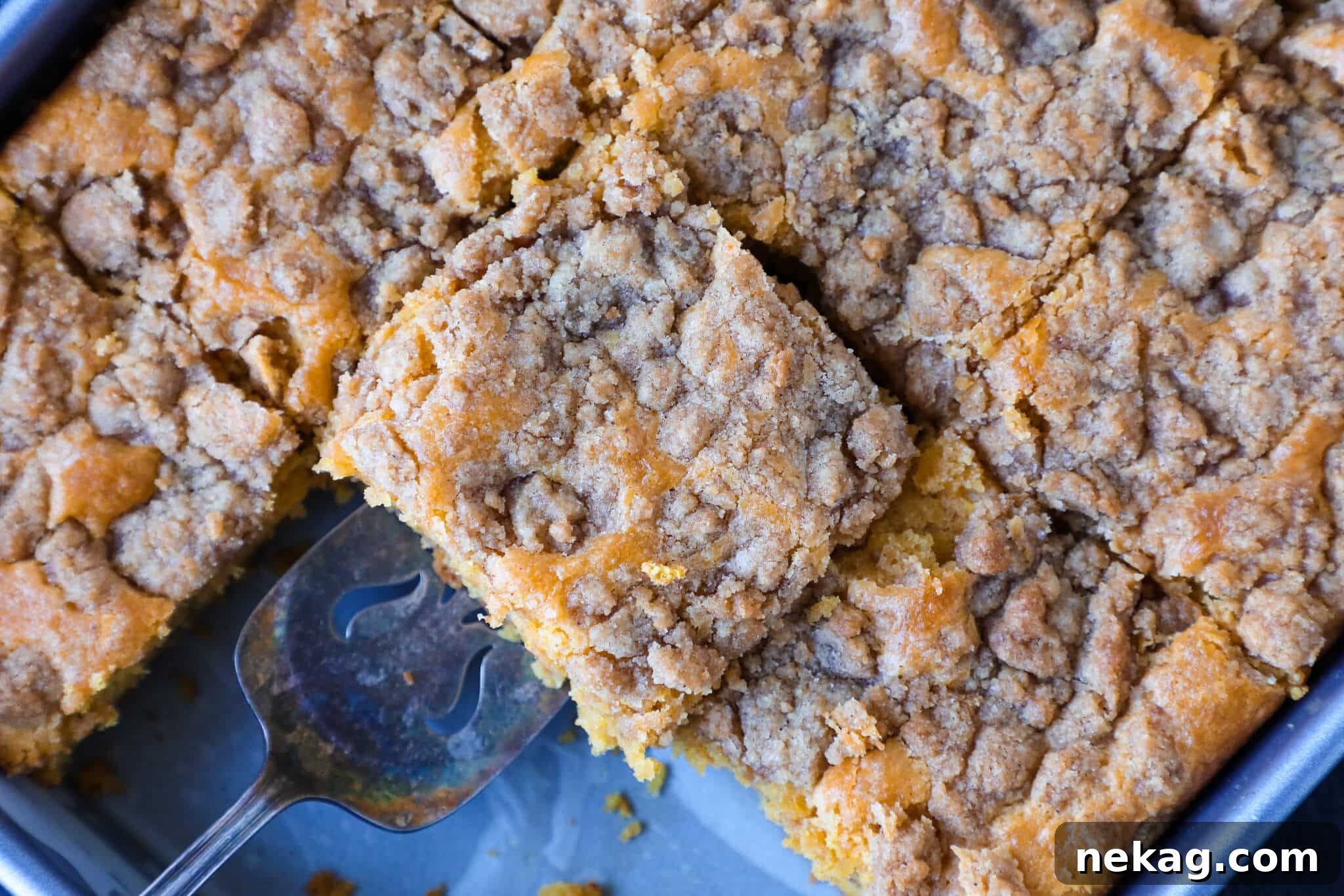 Spiced Pumpkin Crumble Cake 5 Slices of pumpkin coffee cake being served from the baking dish, showcasing its perfect crumb and topping.