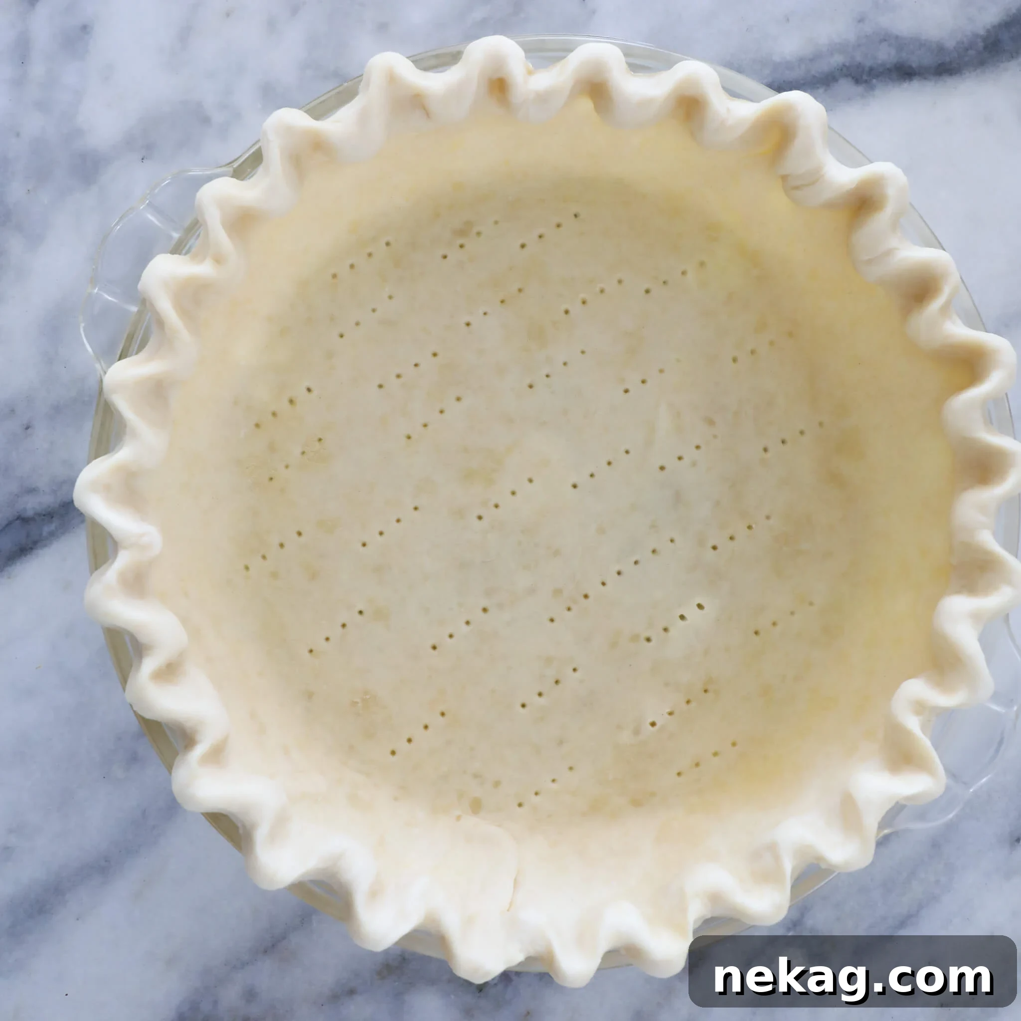 Flawless Crusts The Docking Dilemma Solved 3 Close-up of an unbaked pie crust with visible fork marks from docking, ready for blind baking.