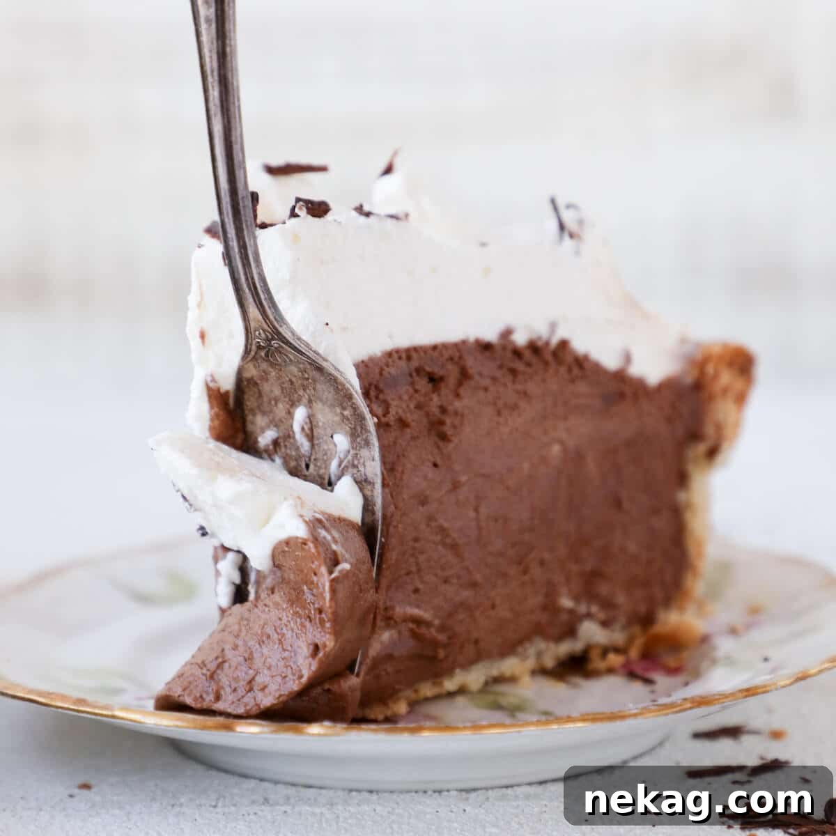 Silken Chocolate Indulgence 5 A slice of French Silk Pie on a white plate with a silver fork resting beside it, highlighting the inviting texture.