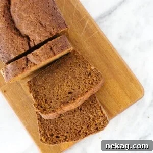 Pumpkin bread slices on a wooden board, set against a marble counter.