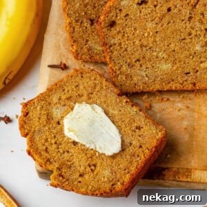 A slice of pumpkin banana bread with melting butter on a warm crumb.