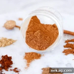 Pumpkin Pie Spice Mix overflowing from a jar, showcasing its rich texture.