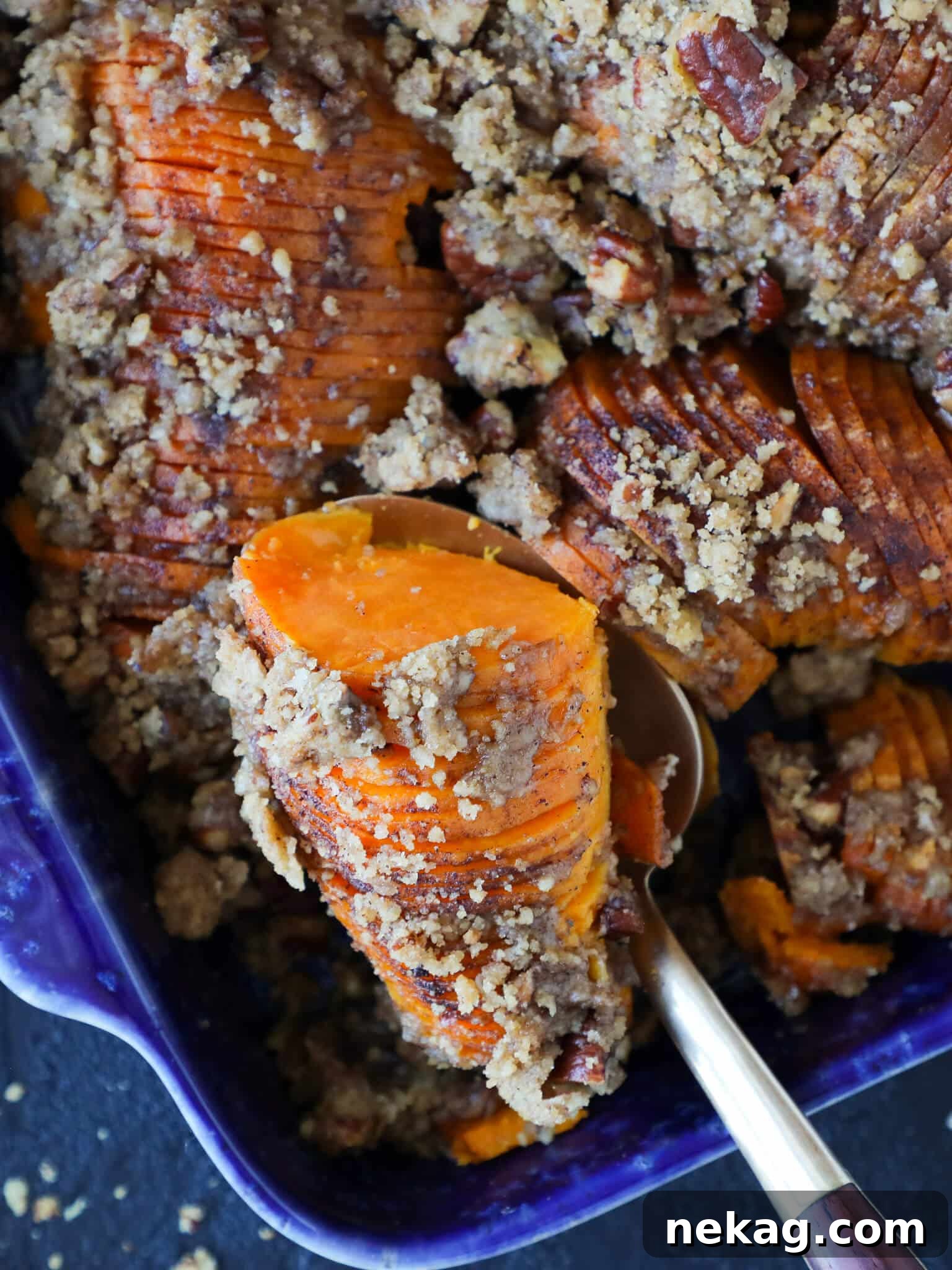 A single serving of Hasselback Sweet Potato Casserole with a silver spoon, highlighting the fanned layers.