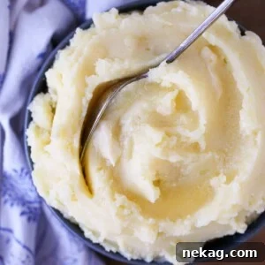 Creamy Mashed Potatoes served in a blue bowl with a vintage spoon.