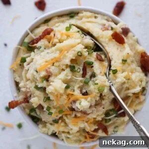 A delicious spoonful of Loaded Mashed Potatoes, revealing bacon bits and chives.