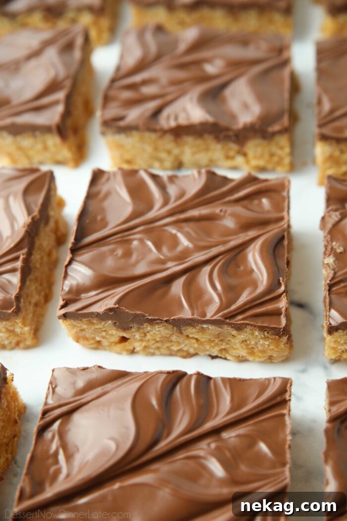 Squares of perfectly cut Scotcharoos — peanut butter rice krispie treats with a glossy chocolate butterscotch topping, ready to serve.