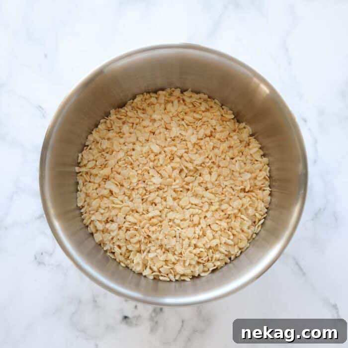 A large glass bowl filled with crispy rice cereal, awaiting the peanut butter mixture.