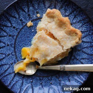 A beautifully sliced Old Fashioned Peach Pie served with a vintage gold fork.