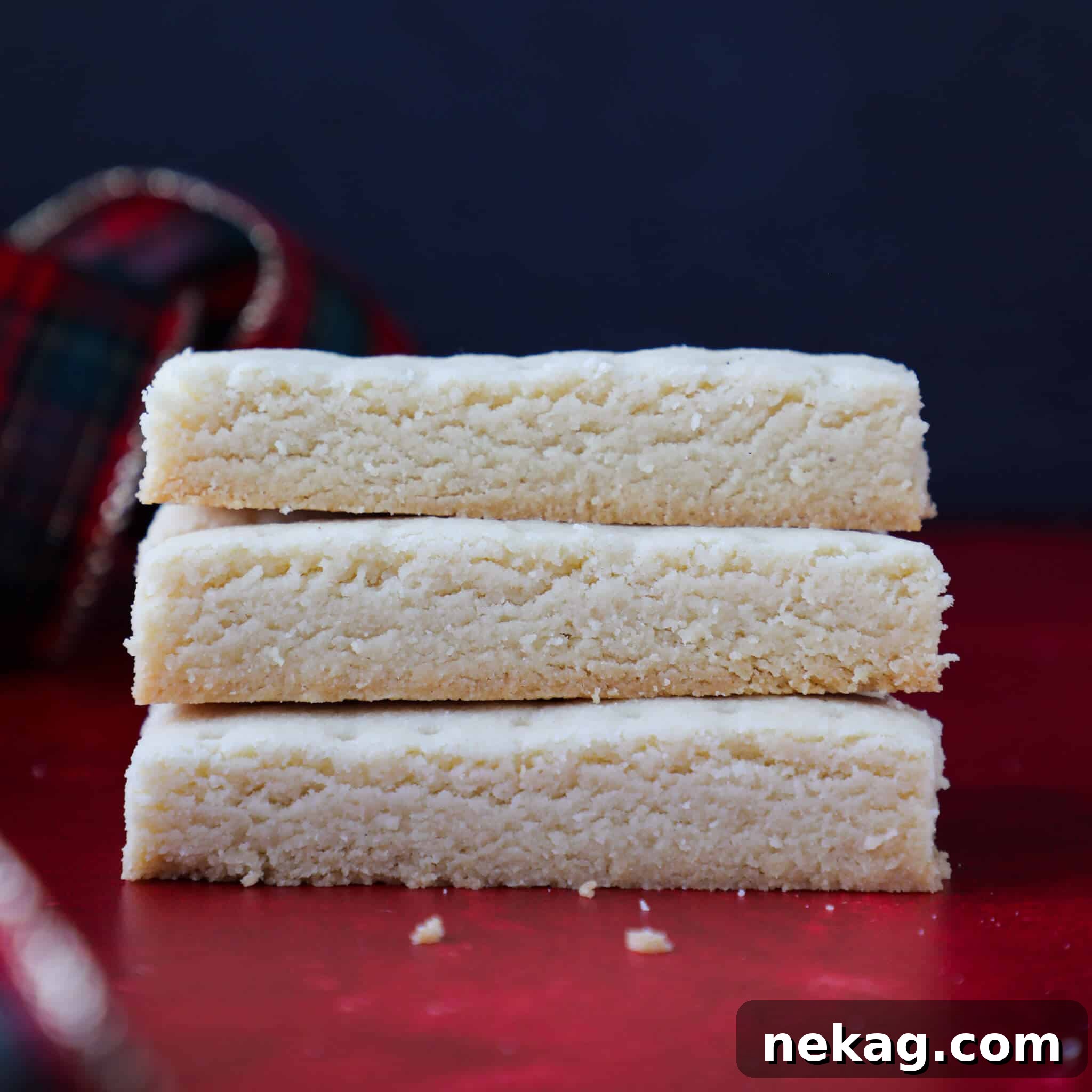 A stack of three scottish shortbread on a red counter.