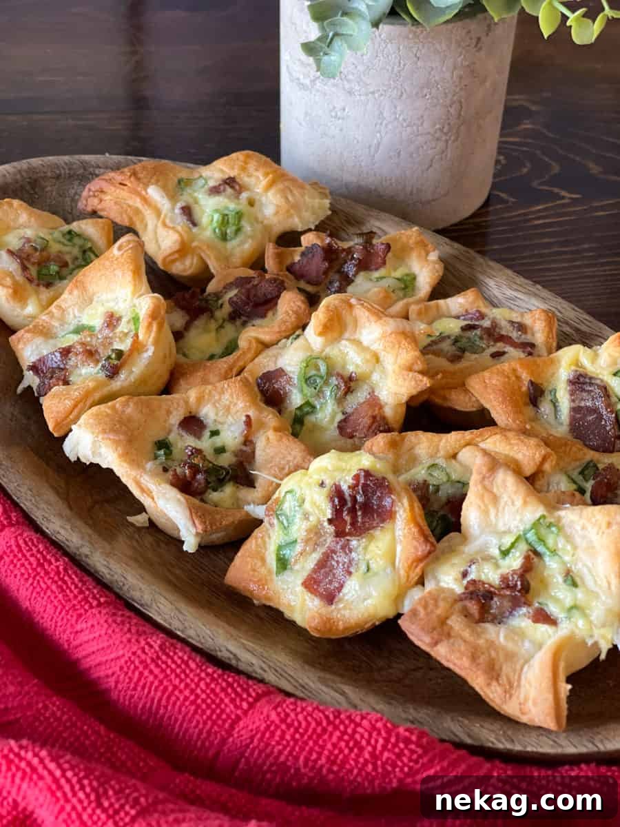 Small, cheesy bacon crescent tartlets artfully arranged in a wooden bowl, ready for serving.
