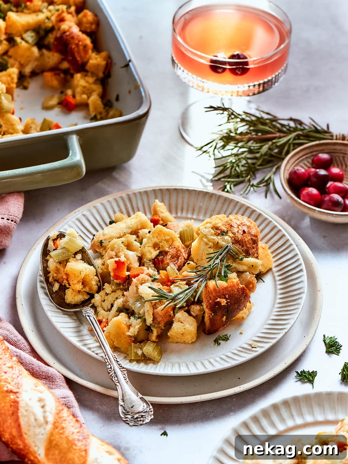 Serving dish brimming with classic cornbread dressing, artfully presented beside fresh cranberries and seasonal herbs.