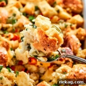 Spoon lifting a serving of Southern cornbread dressing with visible herbs and moist golden crumb.