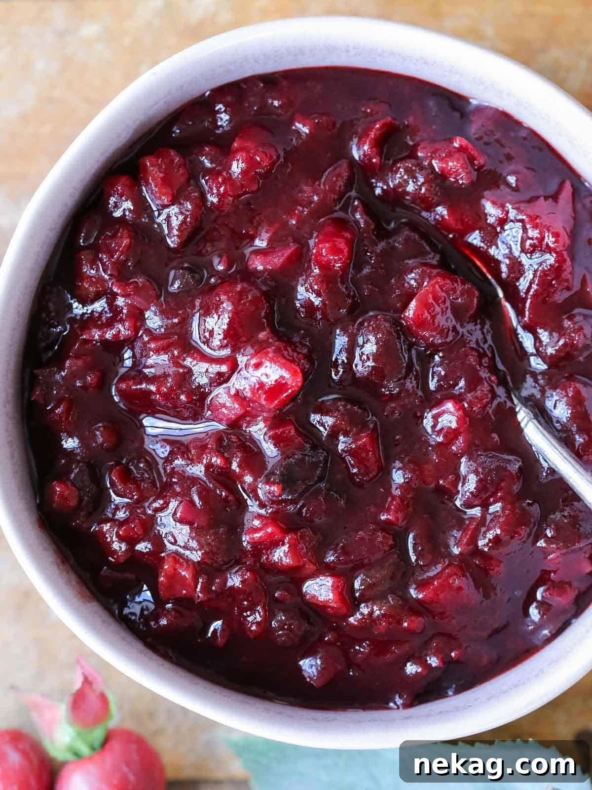 Easy Thanksgiving dinner recipe for vibrant cranberry chutney served in a bowl on a rustic wooden surface.