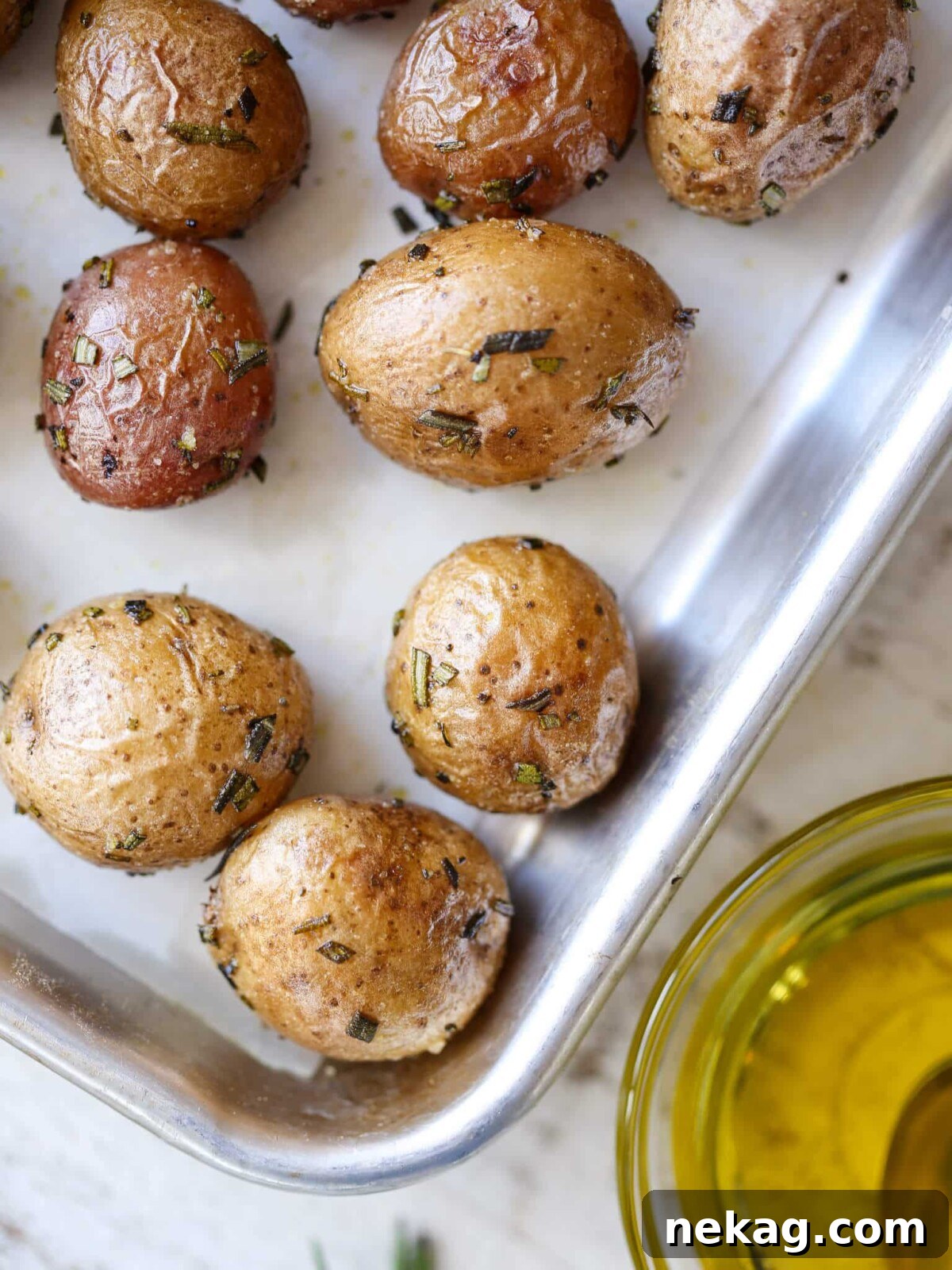 Rosemary Roasted Potatoes spread evenly on a baking sheet with olive oil, ready to be roasted.