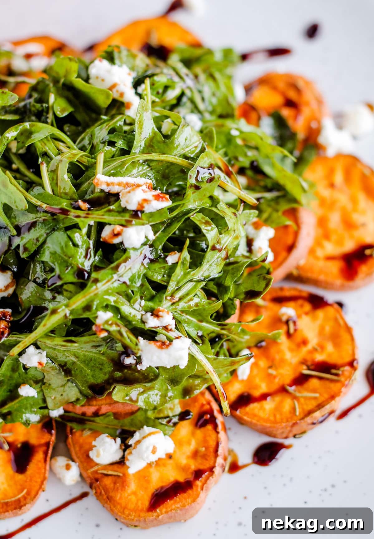 Fresh arugula salad topped with roasted sweet potatoes and a balsamic drizzle, a healthy Thanksgiving side.