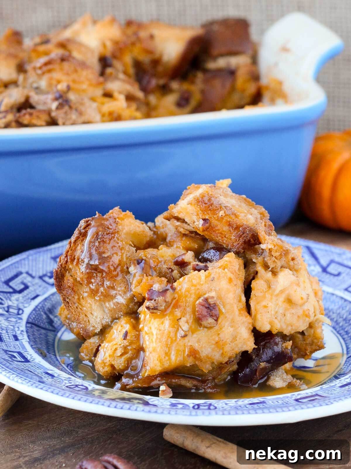 Comforting pumpkin bread pudding served on a blue plate with sauce, against a warm wood background.