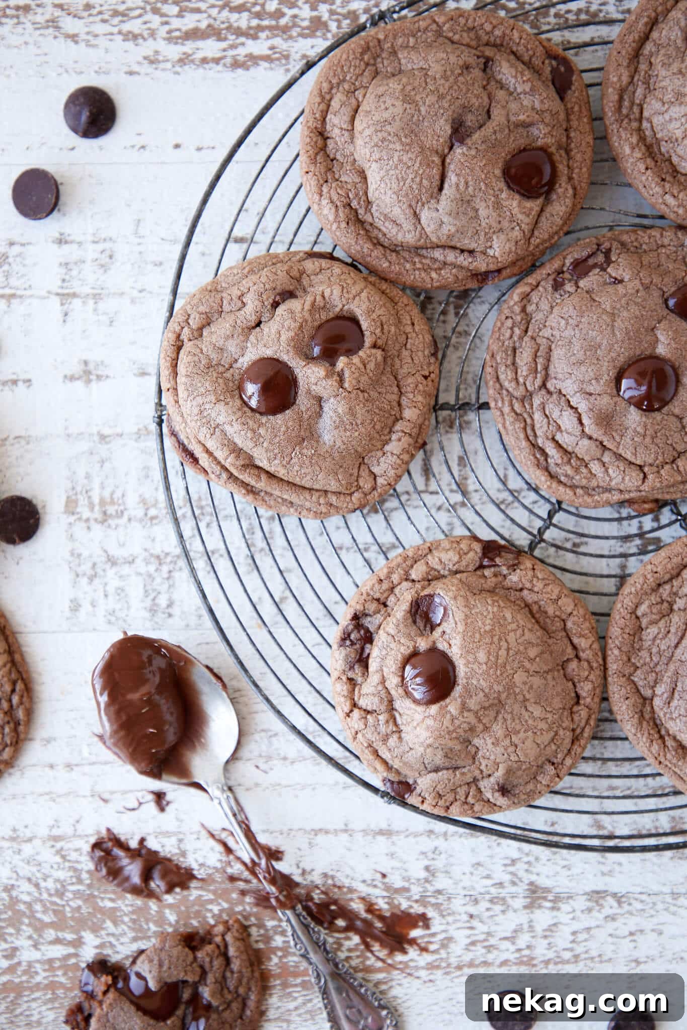 Soft and chewy Nutella Chocolate Chip Cookies on a vintage cooling rack, with a jar of Nutella in the background.