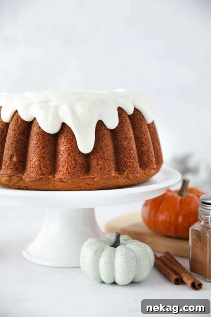 Spiced Pumpkin Crown 3 Side close up view of pumpkin bundt cake with drips of cream cheese frosting coming down the sides.
