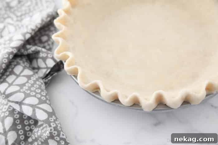 Flaky Butter Pie Crust 16 A close-up view of the perfectly crimped and fluted edges of a pie crust, showcasing the detailed artistry.
