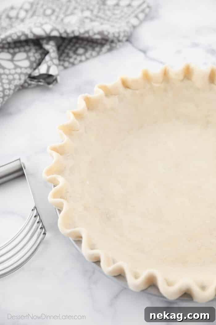 Flaky Butter Pie Crust 4 An artistic angled view of a beautiful all-butter pie crust in a pan, meticulously prepared and ready for baking.