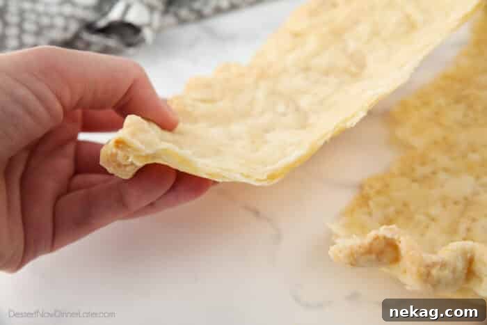 Flaky Butter Pie Crust 6 A close-up side view of a baked pie crust, broken in half to reveal its delicate, flaky layers, showcasing successful pastry technique.