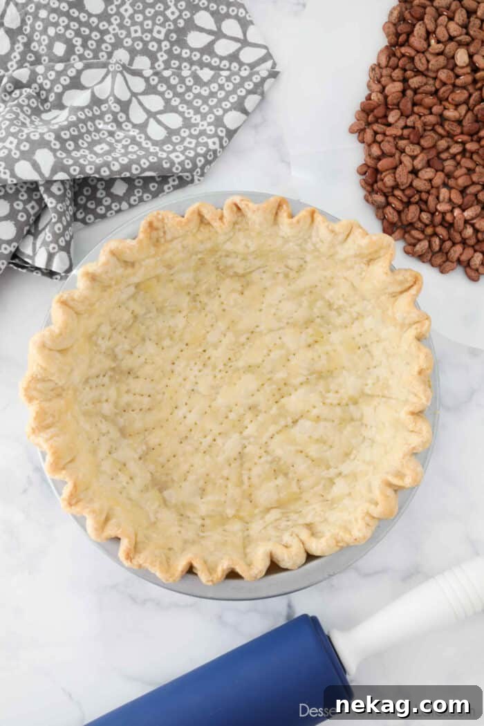 Perfecting Your Blind Baked Pie Crust 2 A perfectly blind baked pie crust, golden brown and crisp, sitting in a pie pan, ready to be filled with a delicious sweet or savory filling.