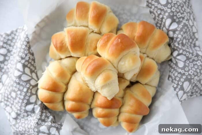 Perfect Homemade Crescent Rolls Video Recipe 3 An overhead shot showcasing a delectable stack of golden homemade crescent rolls nestled in a rustic bread basket.