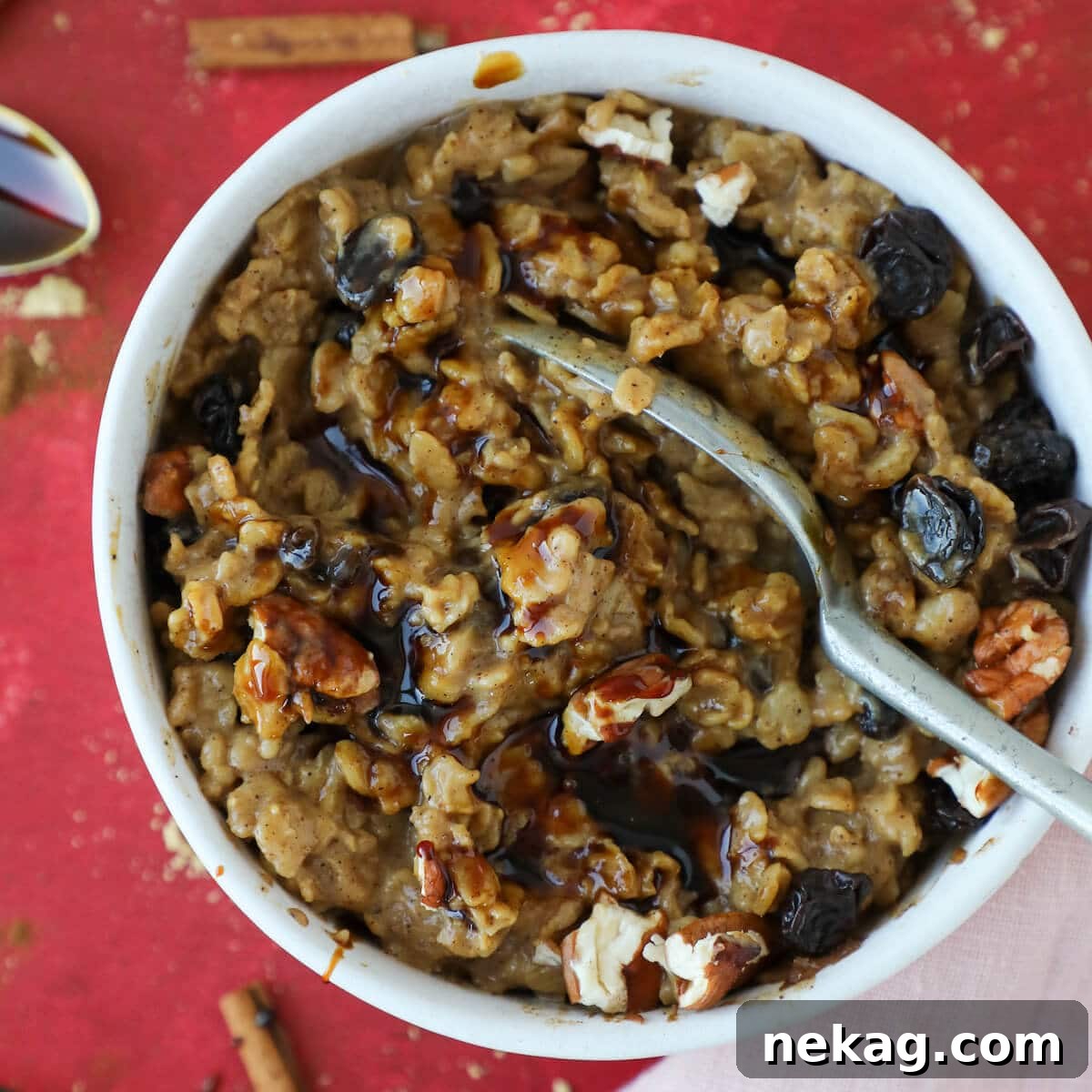 Spiced Gingerbread Oats 3 A spoonful of creamy gingerbread oatmeal topped with a few raisins and pecans, showing its inviting texture.