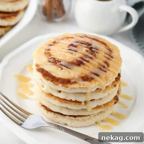Swirled Cinnamon Pancake Stacks 11 Stack of cinnamon roll pancakes with cream cheese glaze drizzled on top.