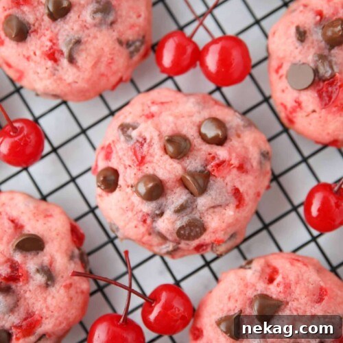 Close up top view of cherry chocolate chip cookies on a wire cooling rack with maraschino cherries on the side.