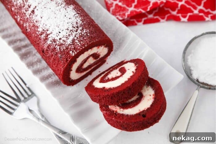 Mastering the Red Velvet Cake Roll 14 Two perfectly cut slices of Red Velvet Roulade, showcasing the spiral of cake and frosting on a white plate.