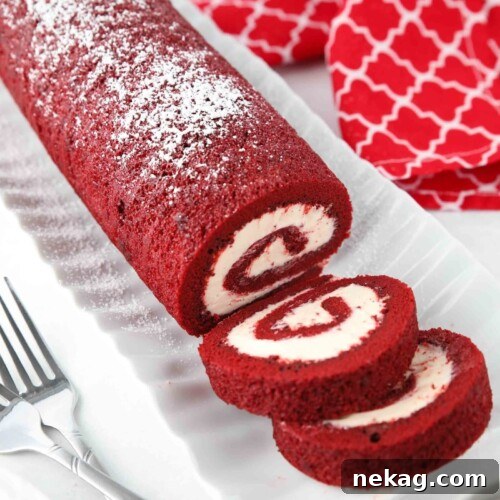 Mastering the Red Velvet Cake Roll 16 A close-up of a Red Velvet Cake Roll on a platter with a couple of slices already cut.