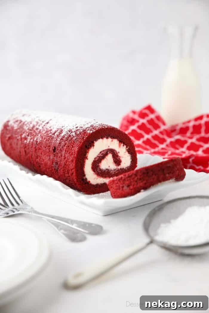 Mastering the Red Velvet Cake Roll 4 Close-up side view of a Red Velvet Cake Roll showing the intricate layers of red cake and white cream cheese frosting.