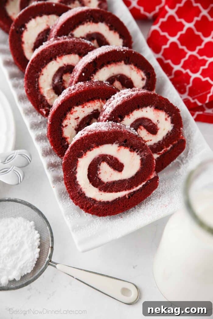 Mastering the Red Velvet Cake Roll 5 Top view of beautifully plated red velvet cake roll slices, dusted with powdered sugar.