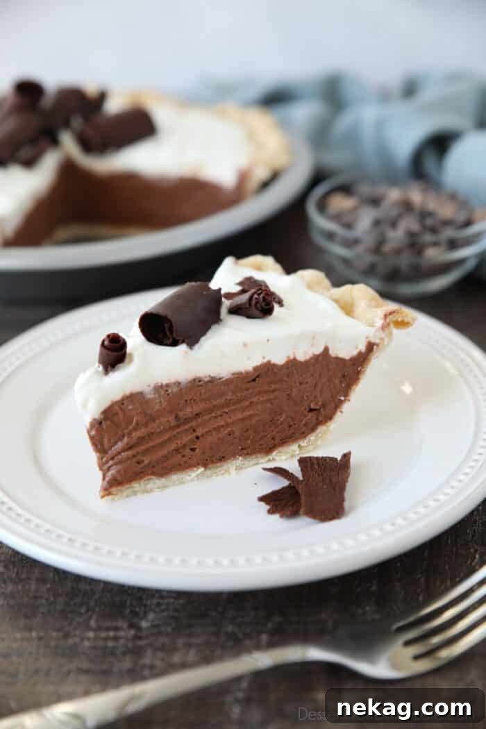 Decadent Chocolate Cream Pie 3 A perfect slice of Chocolate Cream Pie on a plate, revealing a beautifully flaky pastry crust, a generous layer of rich chocolate pudding filling, a fluffy cloud of whipped cream, and delicate chocolate curls on top.