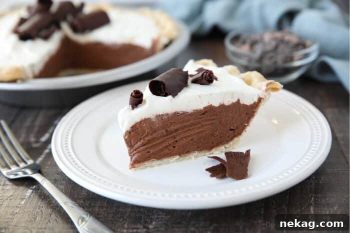 Decadent Chocolate Cream Pie 6 A delicious slice of chocolate cream pie on a white plate, garnished with fine chocolate shavings, emphasizing its rich texture and inviting appearance.