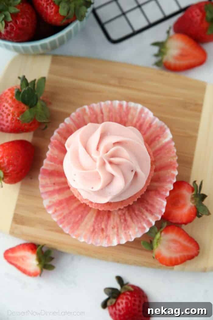 A top-down view of a beautifully decorated cupcake, showcasing strawberry cream cheese frosting perfectly piped onto its surface, highlighting its smooth texture and delightful presentation.