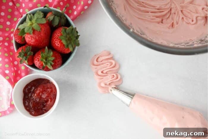 A close-up shot of perfectly piped strawberry cream cheese frosting, showcasing its smooth texture and elegant swirl achieved with a pastry bag and tip.